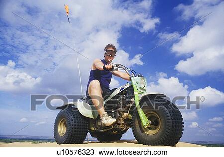 Stock Image - A man astride a 3-wheeled recreational vehicle in Little Sahara State Park, Oklahoma. Fotosearch
