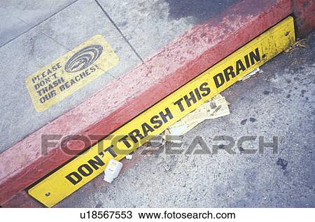 Stock Image - A storm drain littered with garbage. Fotosearch