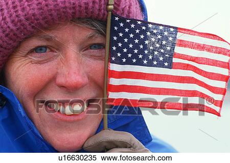 A woman into winter clothing holds a small American flag View Large Photo Image Stock Photography - A woman into winter clothing holds a small American flag. Fotosearch