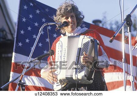 Stock Image - A woman plays the accordion in front of the American flag. Fotosearch