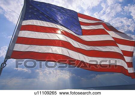 Stock Photography - American Flag Flying Against Blue Sky. Fotosearch