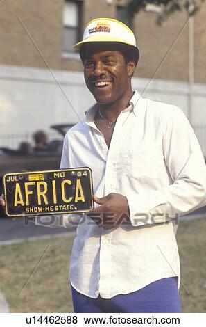 Stock Photo - An African-American man holding a personalized license plate. Fotosearch