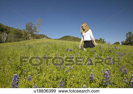Stock Photo - Blonde girl walking through green fields. Fotosearch