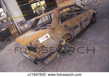 Stock Image - Car burned during 1992 riots, South Central Los Angeles, California. Fotosearch
