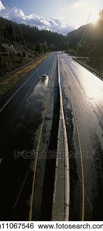 Stock Photograph - Car Travels along wet Road. Fotosearch