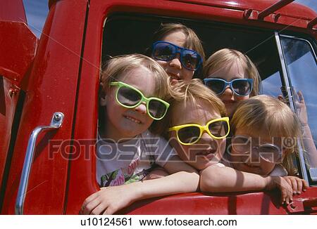 Stock Image - Children wearing sunglasses in a red fire truck. Fotosearch