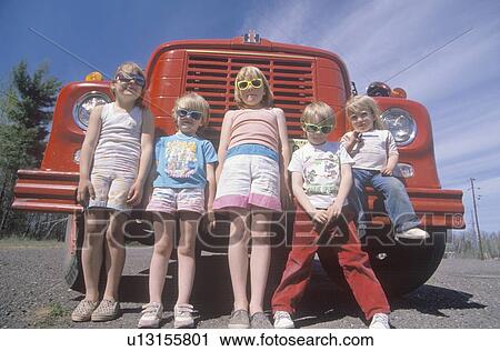 Stock Image - Children wearing sunglasses with a fire truck. Fotosearch