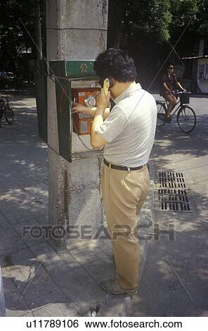 Chinese man making call at pay phone View Large Photo Image Stock Photograph - Chinese man making call at pay phone. Fotosearch