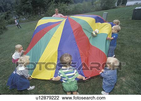 Stock Image - Daycare children playing a parachute game. Fotosearch