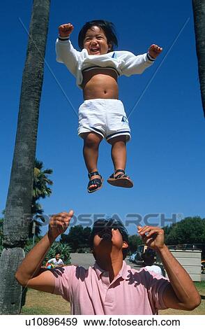 Stock Photo - Filipino father tossing baby in the air. Fotosearch