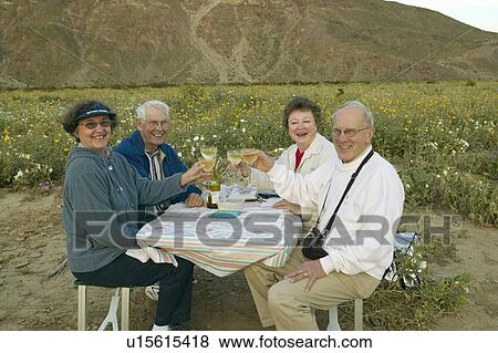Stock Photo - Four senior citizens drinking white wine in field. Fotosearch