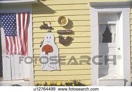 Stock Photo - Halloween decorations and an American flag on a yellow wooden house. Fotosearch