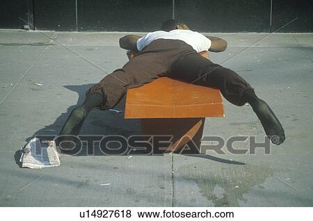 Stock Photo - Homeless black man sleeping on a park bench. Fotosearch