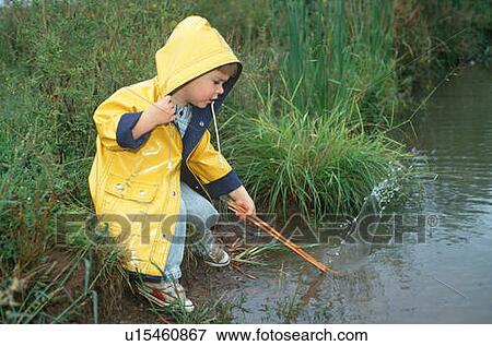 Little boy in yellow raincoat playing at edge of a stream View Large Photo Image Stock Photo - Little boy in yellow raincoat playing at edge of a stream. Fotosearch