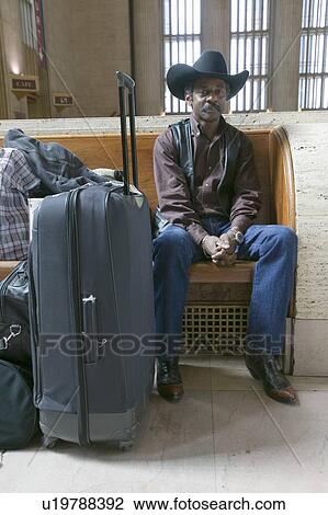 Stock Image - Man in cowboy hat waiting at train station. Fotosearch