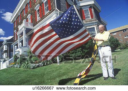 Stock Photo - Man Raising American and Maryland Flags, Cape May, New Jersey . Fotosearch