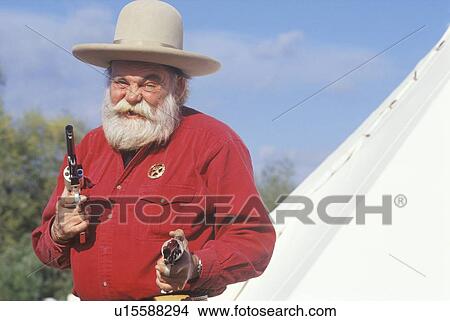 Old West gunslinger drawing guns during historical reenactment View Large Photo Image Picture - Old West gunslinger drawing guns during historical reenactment. Fotosearch