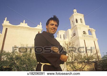 Stock Image - Padre stands in front of Mission San Xavier Del Bac. Fotosearch