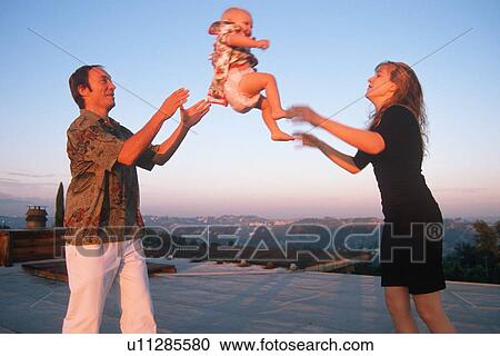 Stock Image - Parents tossing their baby to each other. Fotosearch