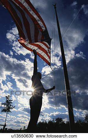 Stock Image - Park Ranger raising the American flag on its flagpole. Fotosearch