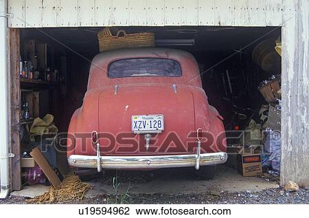 Stock Image - Rear view of antique red car in garage. Fotosearch