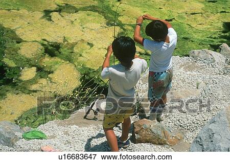 Stock Photo - Rear view of two boys fishing at a pond. Fotosearch