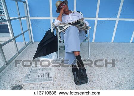 Stock Photograph - Retired man with newspaper sleeping in a lawn chair. Fotosearch