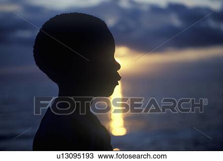 Stock Image - Silhouette of young Jamaican at sunset. Fotosearch