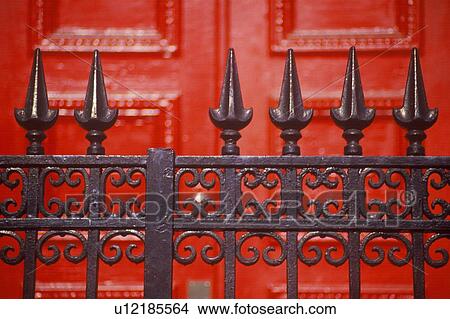 Picture - Spike wrought iron fence in front of red door. Fotosearch