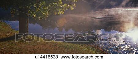 Stock Photo - This is a row boat sitting at the edge of a pond in autumn. The pond is near Route 10.. Fotosearch