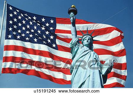Stock Photography - This is an American flag on a flagpole waving in the wind set against a blue sky. Fotosearch