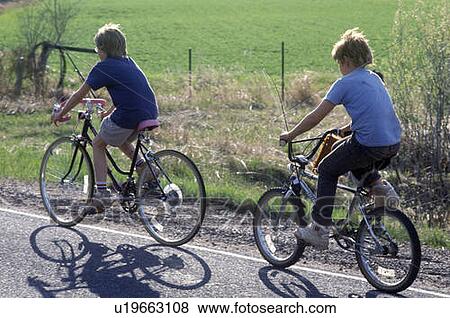 Two boys riding bicycles on rural road View Large Photo Image Stock Photo - Two boys riding bicycles on rural road. Fotosearch