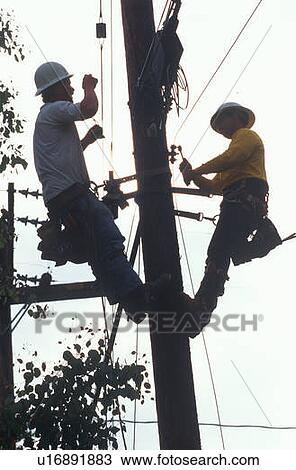 Two repairmen on a telephone pole working on the cable View Large Photo Image Stock Image - Two repairmen on a telephone pole working on the cable. Fotosearch