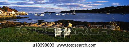 Stock Image - Two white lawn chairs facing toward the nearby harbor. Fotosearch