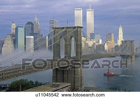 Stock Image - View of New York skyline, Brooklyn Bridge over the East River and tugboat in fog, NY. Fotosearch