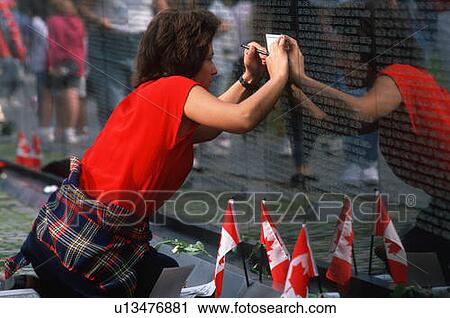 Stock Image - Woman tracing a name of a soldier at Vietnam Memorial Wall, Washington D. C.. Fotosearch
