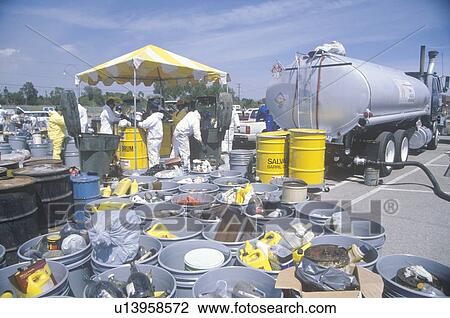 Stock Image - Workers handling toxic household wastes at waste cleanup site on Earth Day. Fotosearch