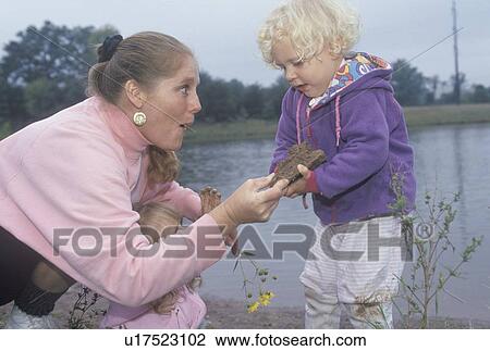 Stock Image - A childcare worker playing with children by a lake. Fotosearch