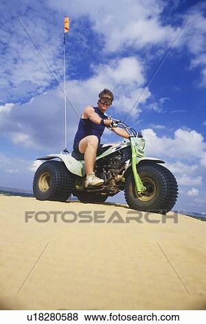 Stock Photo - A man riding a three-wheeled all-terrain vehicle in Little Sahara State Park, Oklahoma. Fotosearch