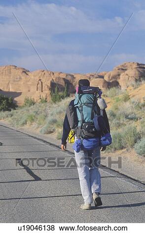 Stock Photo - A man walking on the highway, Arches National Park, UT. Fotosearch