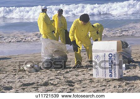 A man with adsorbent materials to clean up oil washed ashore after a spill View Large Photo Image Stock Photo - A man with adsorbent materials to clean up oil washed ashore after a spill. Fotosearch