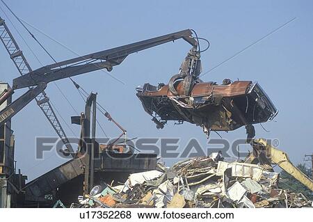 Stock Photo - A wrecking crane lowering a demolished automobile onto a pile of junk. Fotosearch