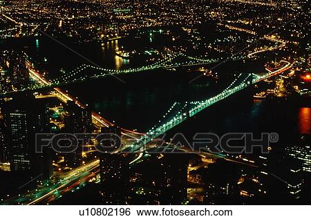 Stock Photograph - Aerial view of Manhattan and Brooklyn Bridges at night in Manhattan, New York City, New York. Fotosearch
