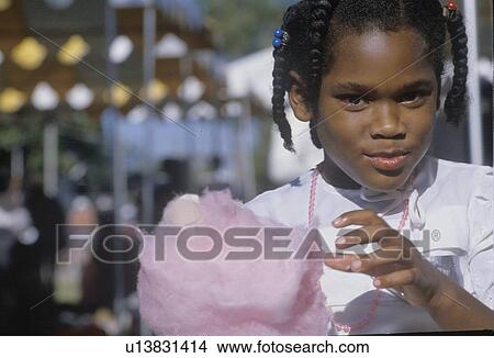 Picture - An African-American girl eating cotton candy. Fotosearch
