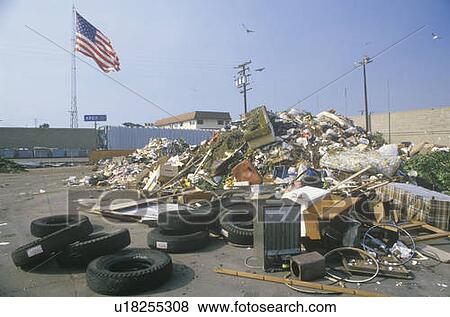 Stock Photo - An American flag waving in the distance behind a dump site. Fotosearch