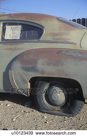 Stock Photo - An old car with a flat tire has a not for sale sign in its window. Fotosearch