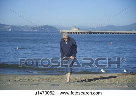 Stock Image - Barefoot man walking at beach, San Francisco, California. Fotosearch