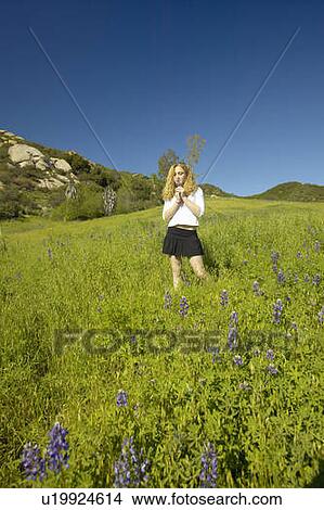 Picture - Blonde girl walking through green fields. Fotosearch