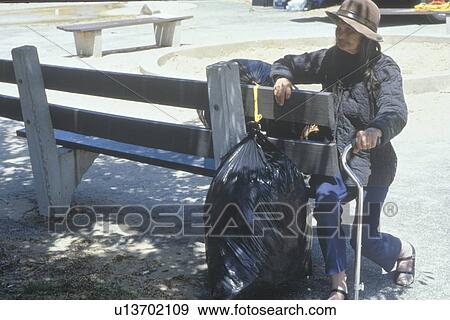 Elderly homeless woman sitting on park bench View Large Photo Image Stock Photo - Elderly homeless woman sitting on park bench. Fotosearch