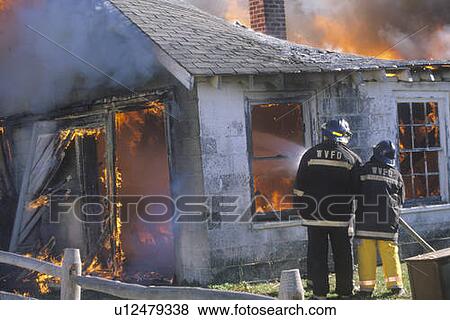 Stock Photo - Firemen putting out a house on fire. Fotosearch